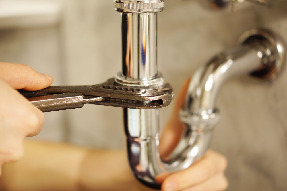 Plumber adjusting chrome pipe with wrench